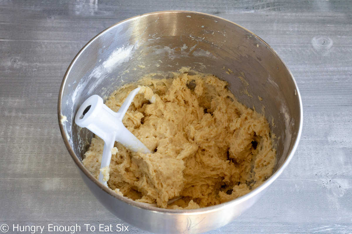 Bread dough in a mixing bowl with mixer beater.