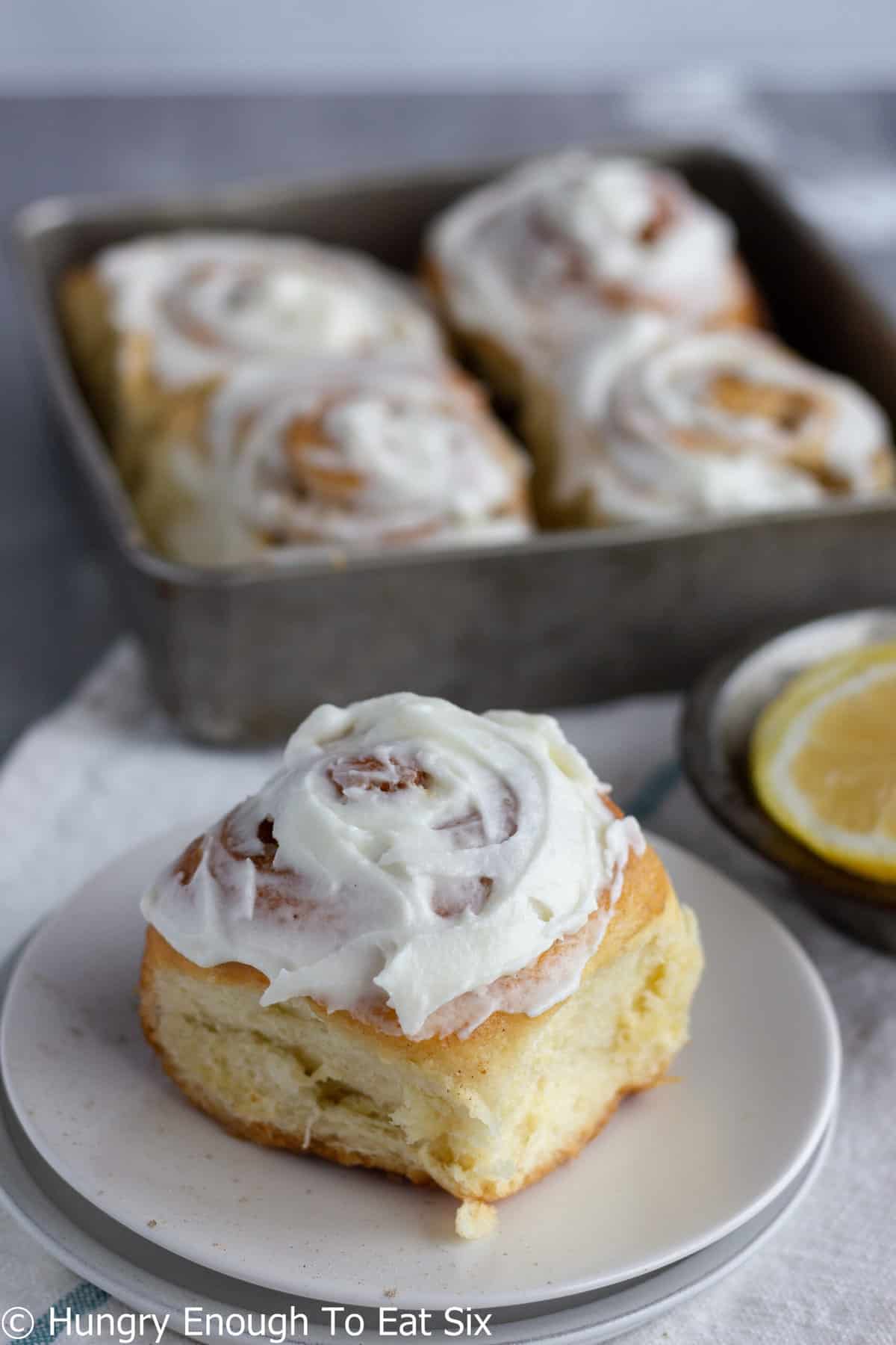 Lemon roll topped with frosting with panful behind.