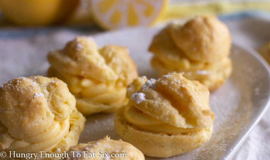Cream puffs with lemon filling on a white plate dusted with confectioner's sugar
