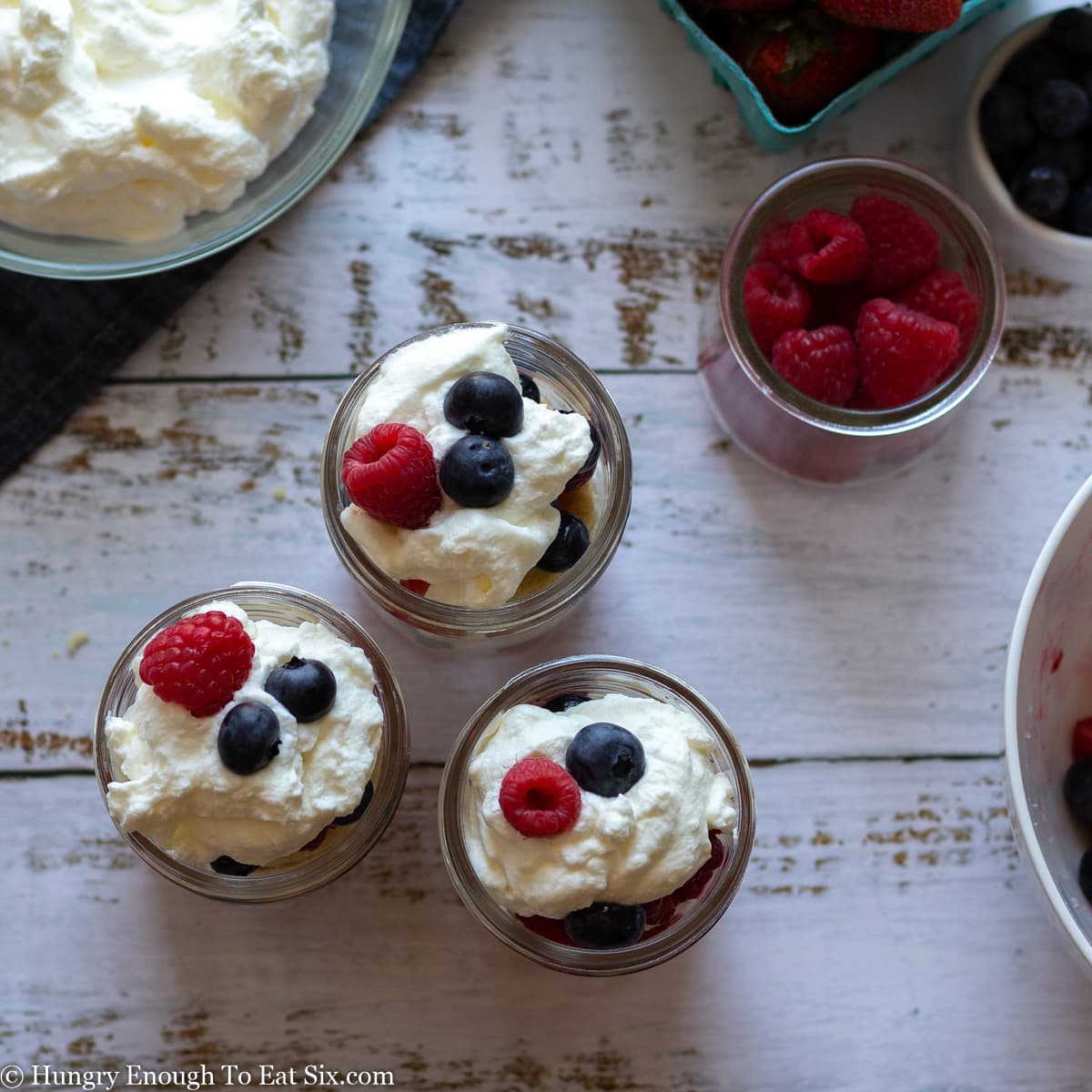 Looking down on three jars with cream and berries in them