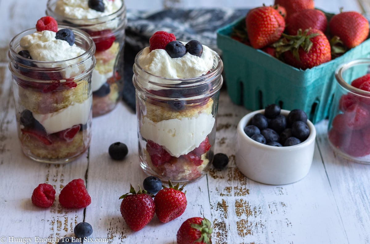 Trifle in a mason jar surrounded by blueberries and strawberries