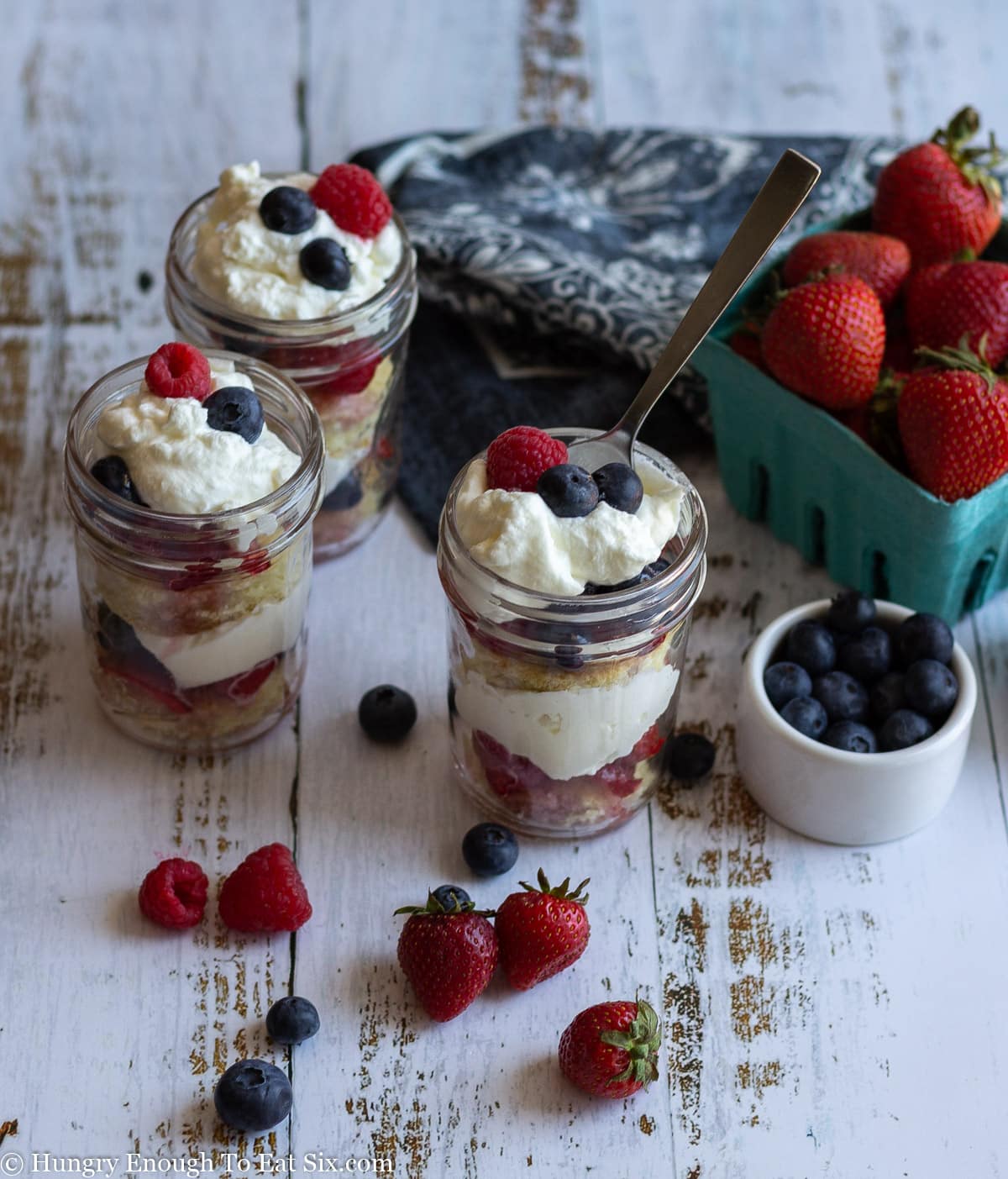 Three mason jars holding layered trifles of fruit and cream