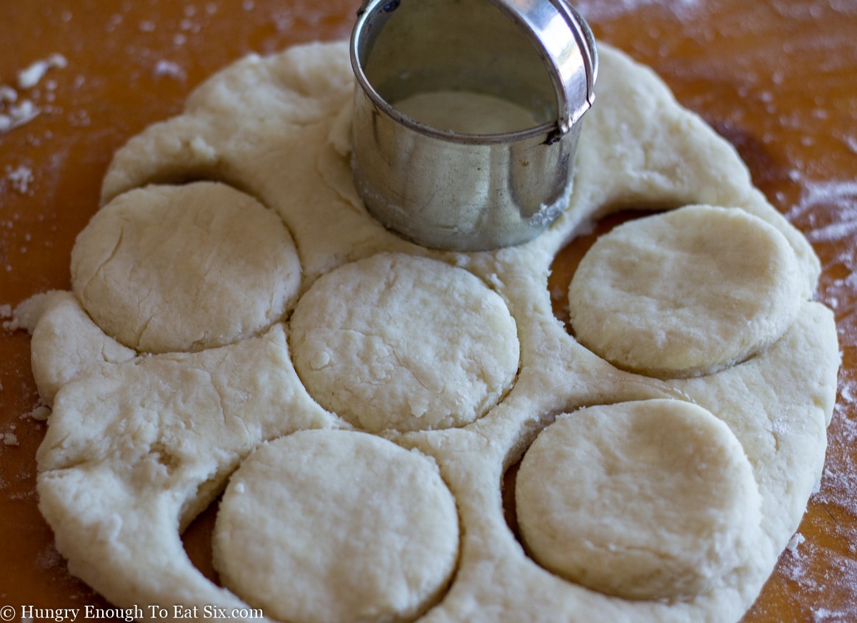 Cookie cutter on rolled out dough with dough circles cut out.