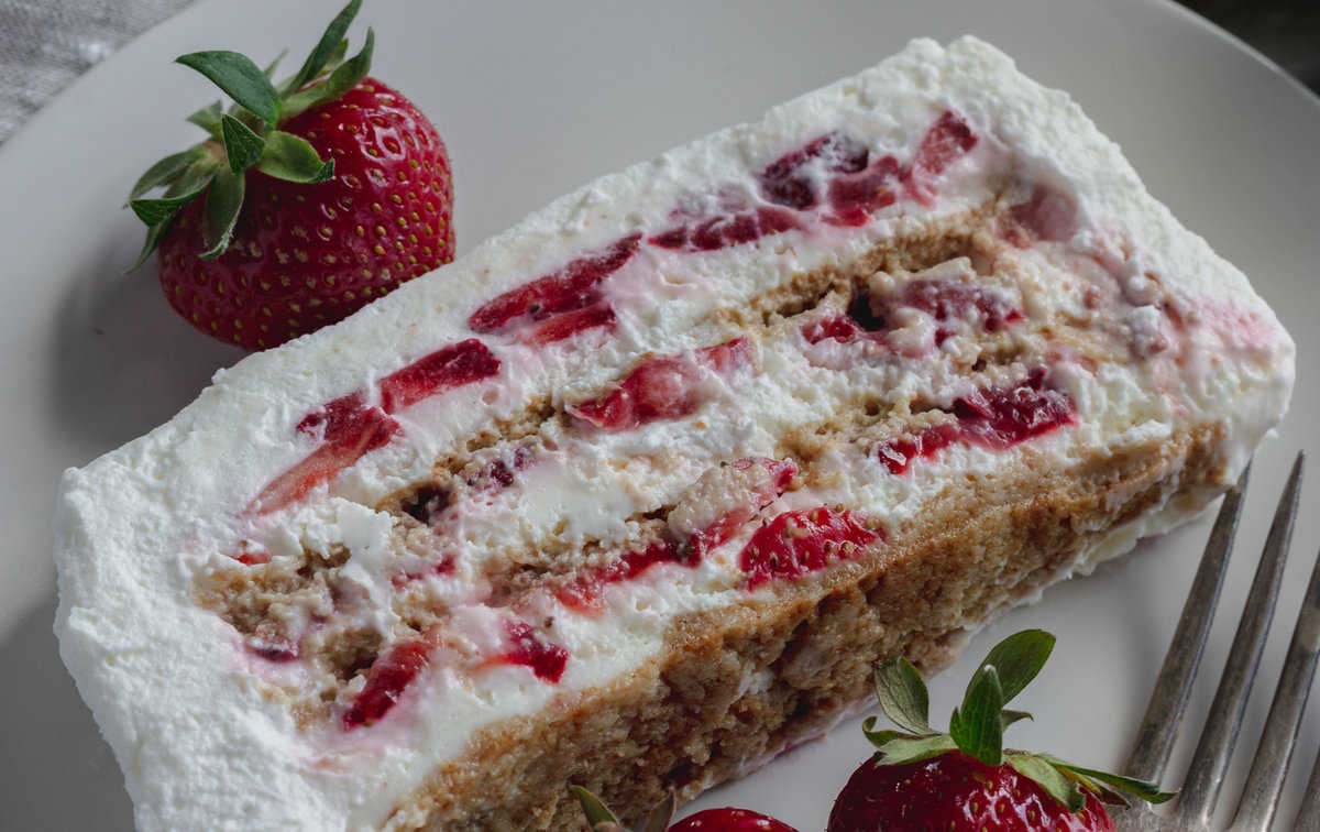 Layers of berries, cream, and graham crackers in a cake