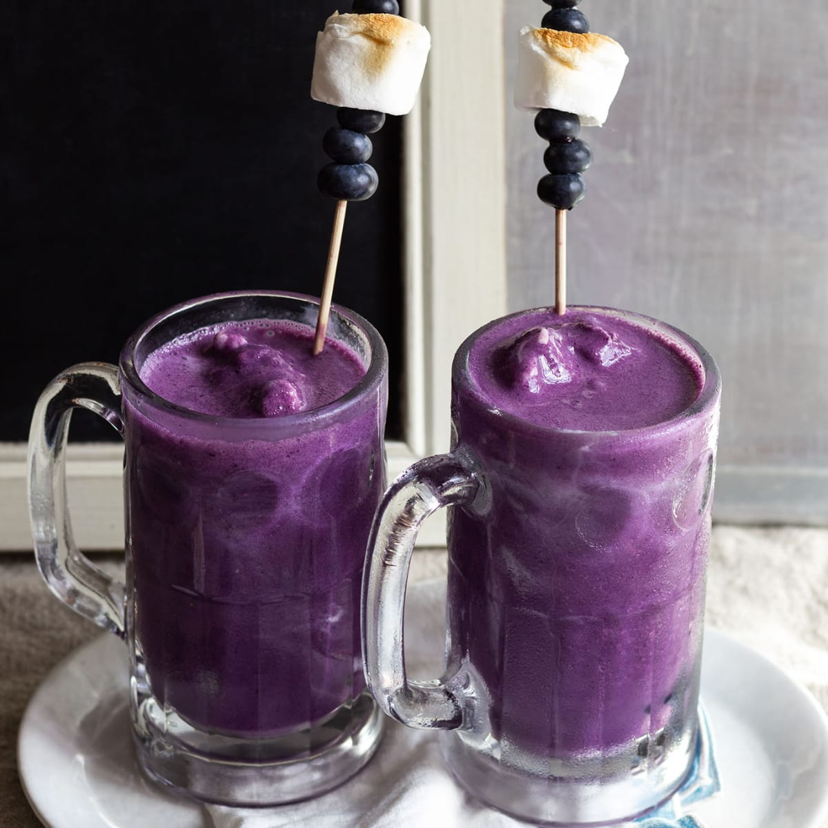 Blueberry milkshakes in glasses with skewers