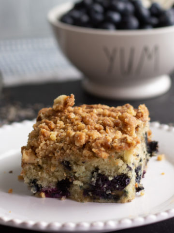 Blueberry coffee cake slice on a white plate.
