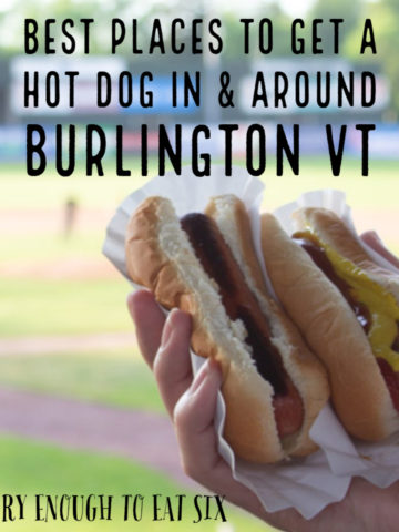 Two hot dogs in a hand with baseball field behind