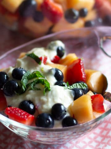 Bowl of fresh fruit salad with mint and cream.