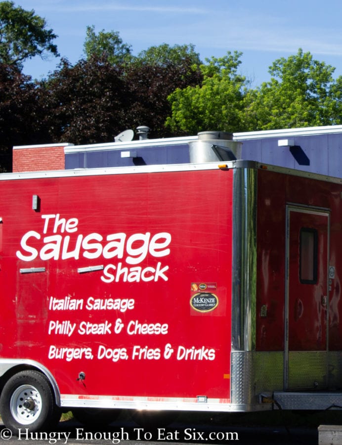 Side of The Sausage Shack food truck, red truck with white lettering. 
