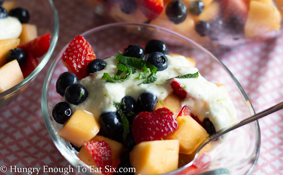 Glass dish with fruit salad and creamy sauce.