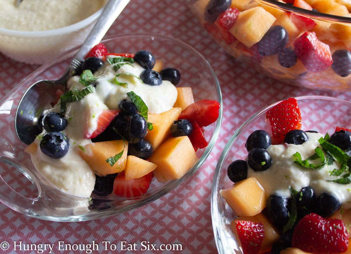 Fruit salad in bowls with dollops of creamy dressing.