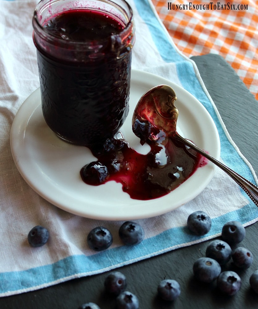 Blueberry sauce in a jar with a ladle on a plate