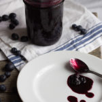 Blueberry sauce in a mason jar on a white cloth.