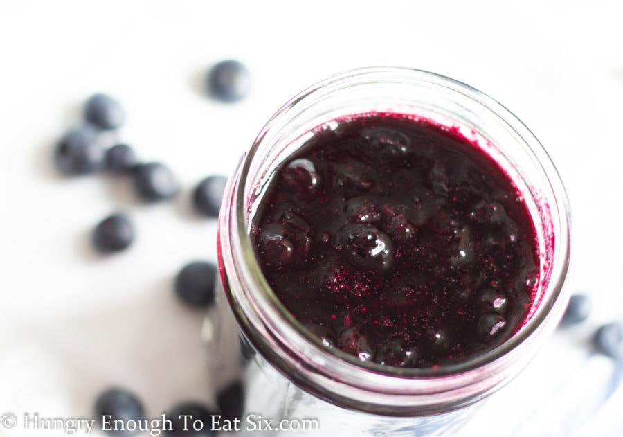 Blueberry sauce inside a mason jar on a white background.
