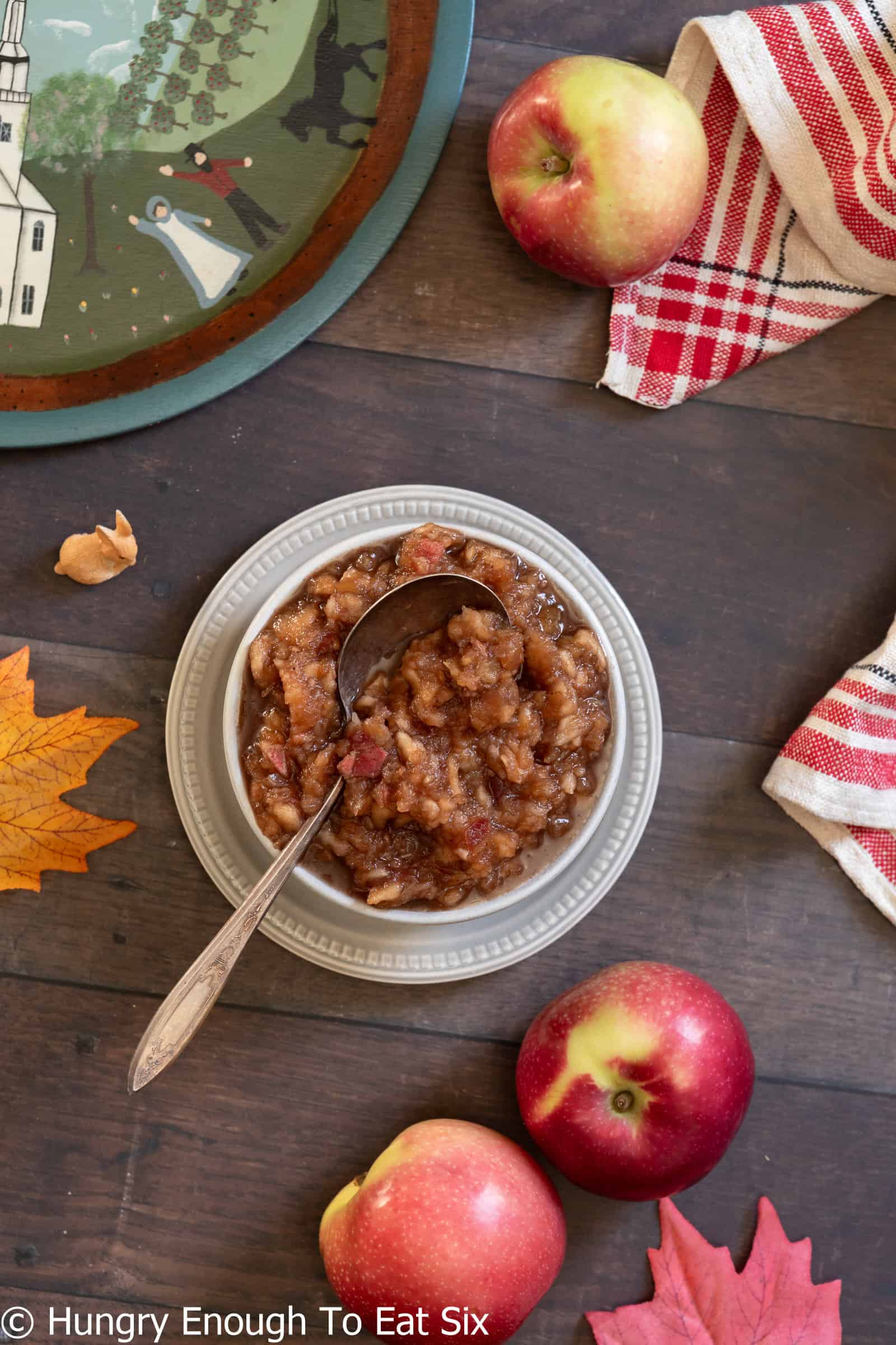 Rustic homemade applesauce in a bowl near apples and leaves.