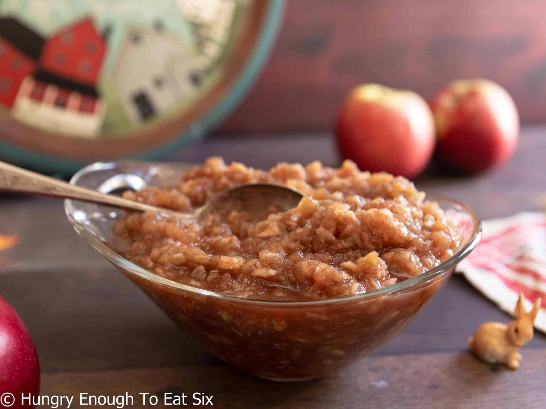 Chunky applesauce in a glass dish with a spoon.