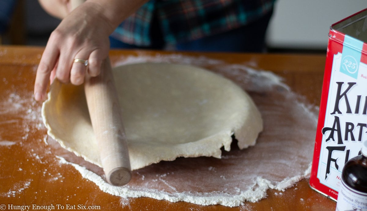 Pie dough over pie plate on floured surface.