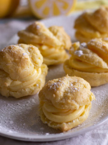 Cream puffs with yellow lemon filling on a white plate.