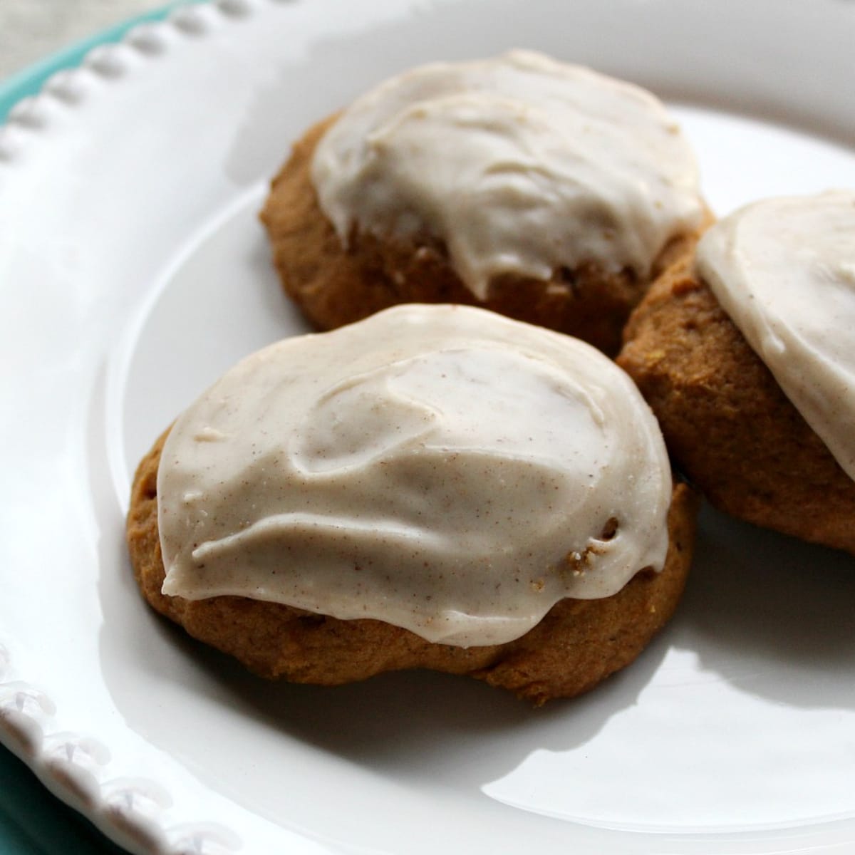 White plate with brown cookies topped with frosting