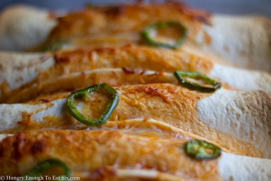 Close-up of jalapenos and baked cheese on burritos.