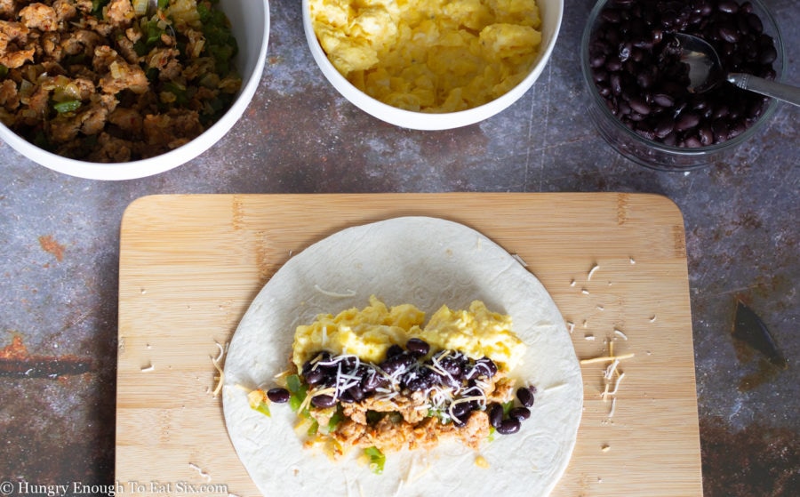 Breakfast burrito fillings in bowls and on a tortilla.
