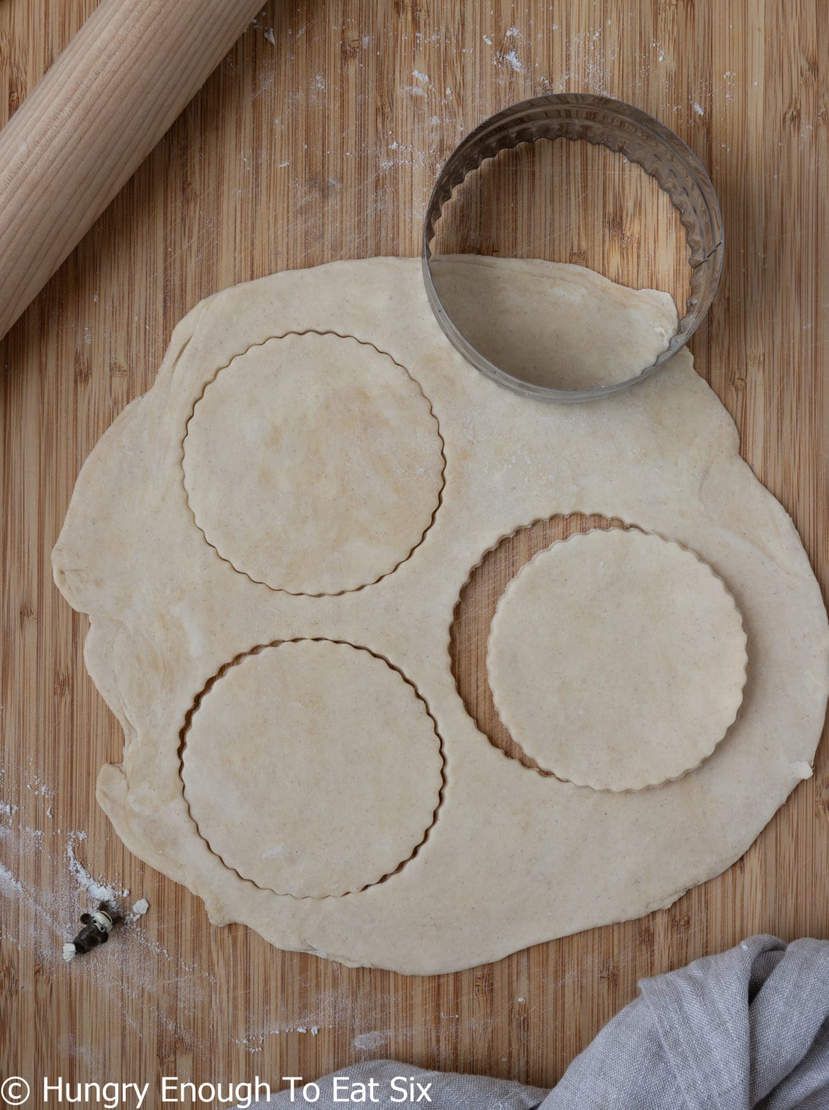 Rolled out pastry dough with circles cut out.