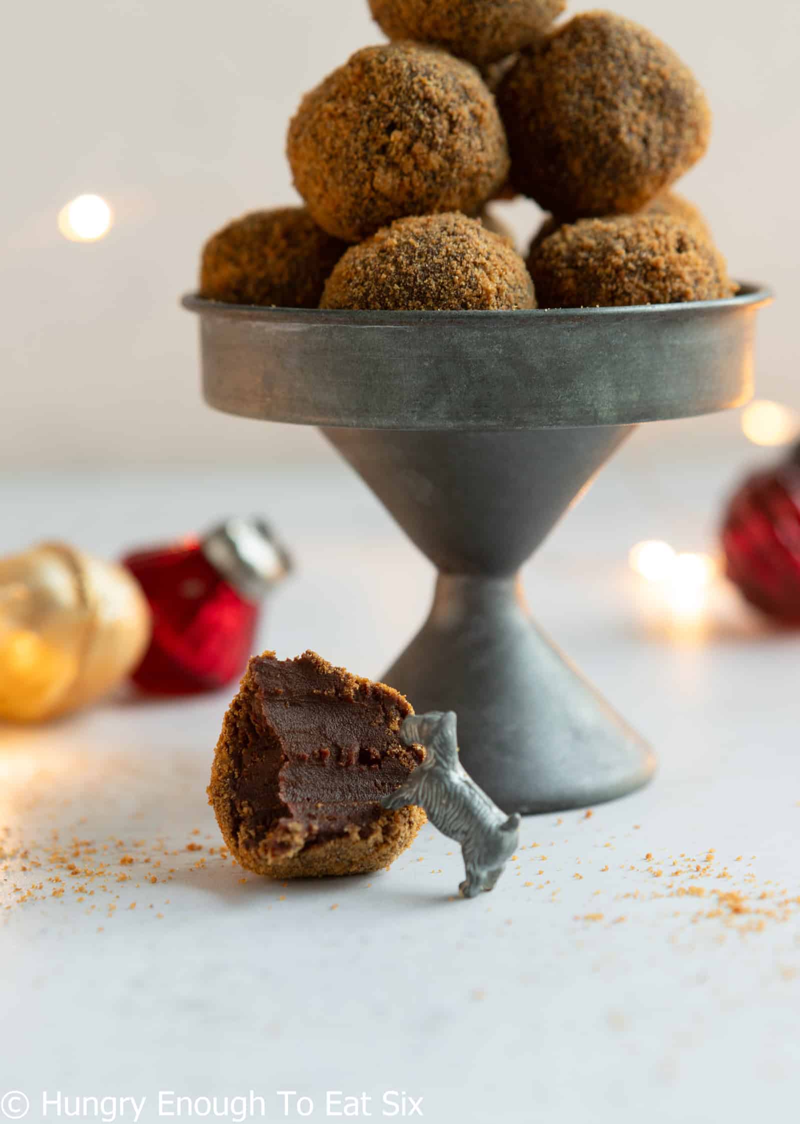 Ginger cookie chocolate truffles in a dish and one with a bite taken out on the table.