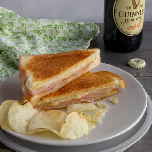 Grilled sandwich with chips on plate.