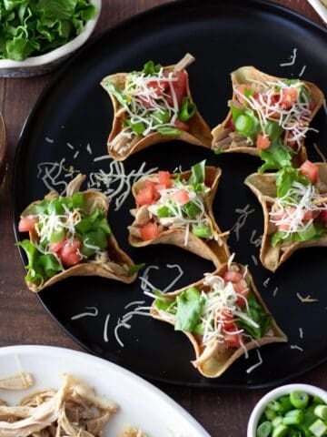 Small Taco Cups filled with slow cooker chicken, lettuce, tomato, and cheese.