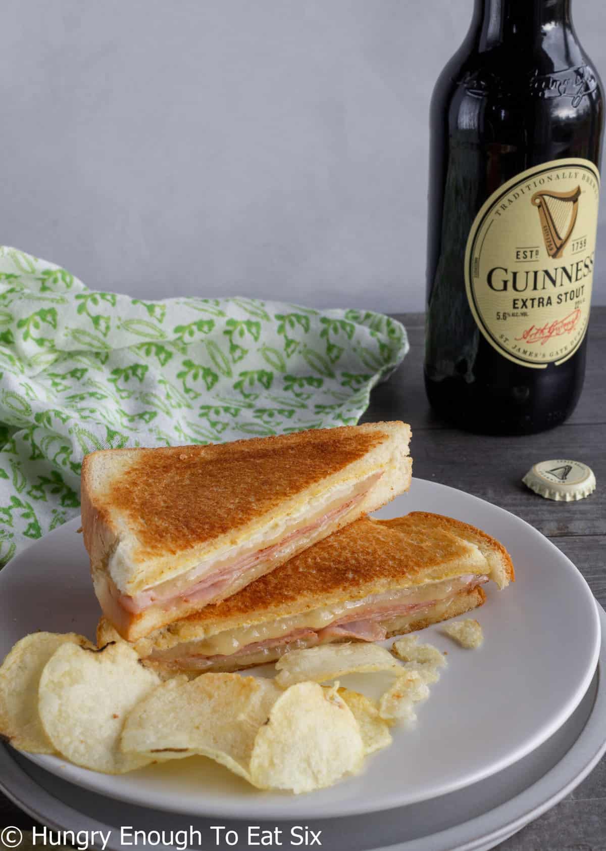 Grilled cheese and ham toastie with chips and a beer.