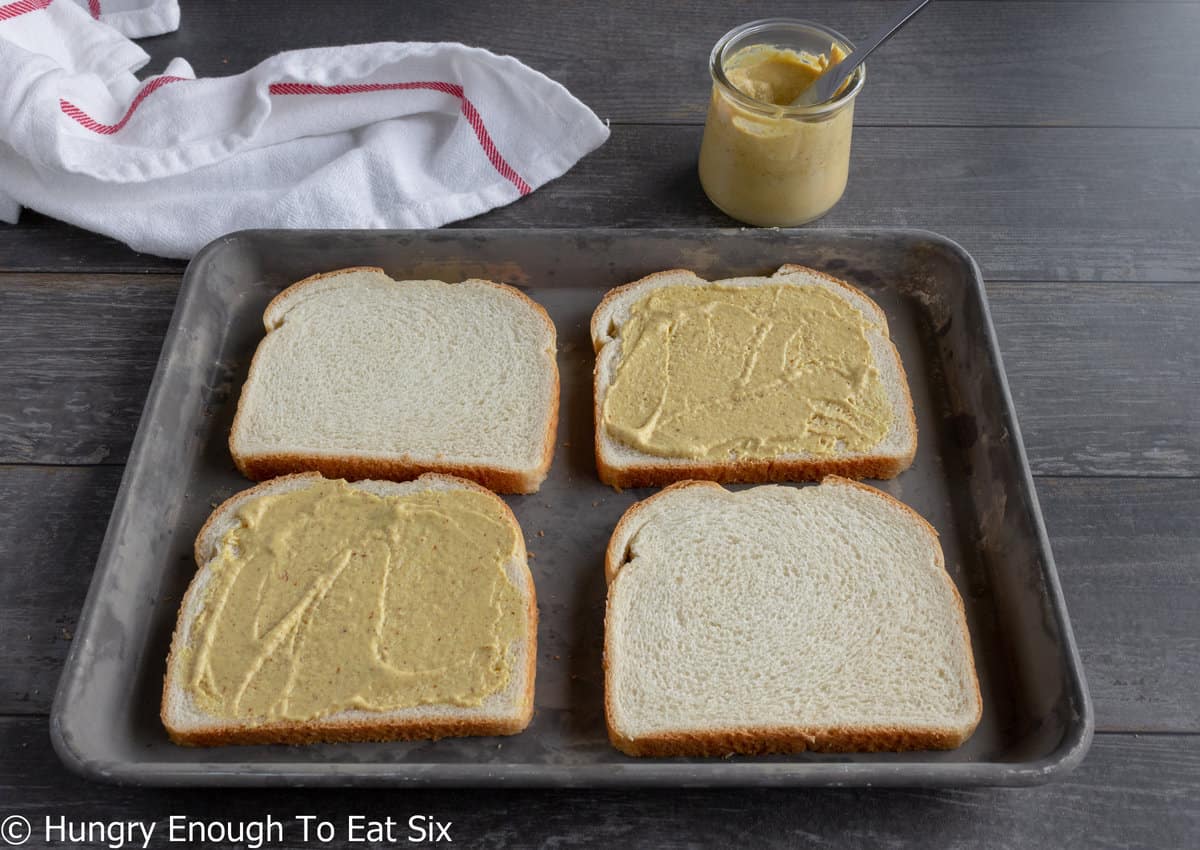 Four slices of bread, two with mustard.
