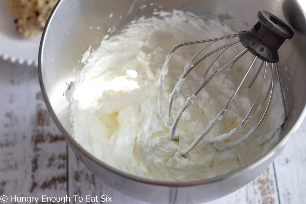 Mixing bowl with fresh whipped cream and whisk.
