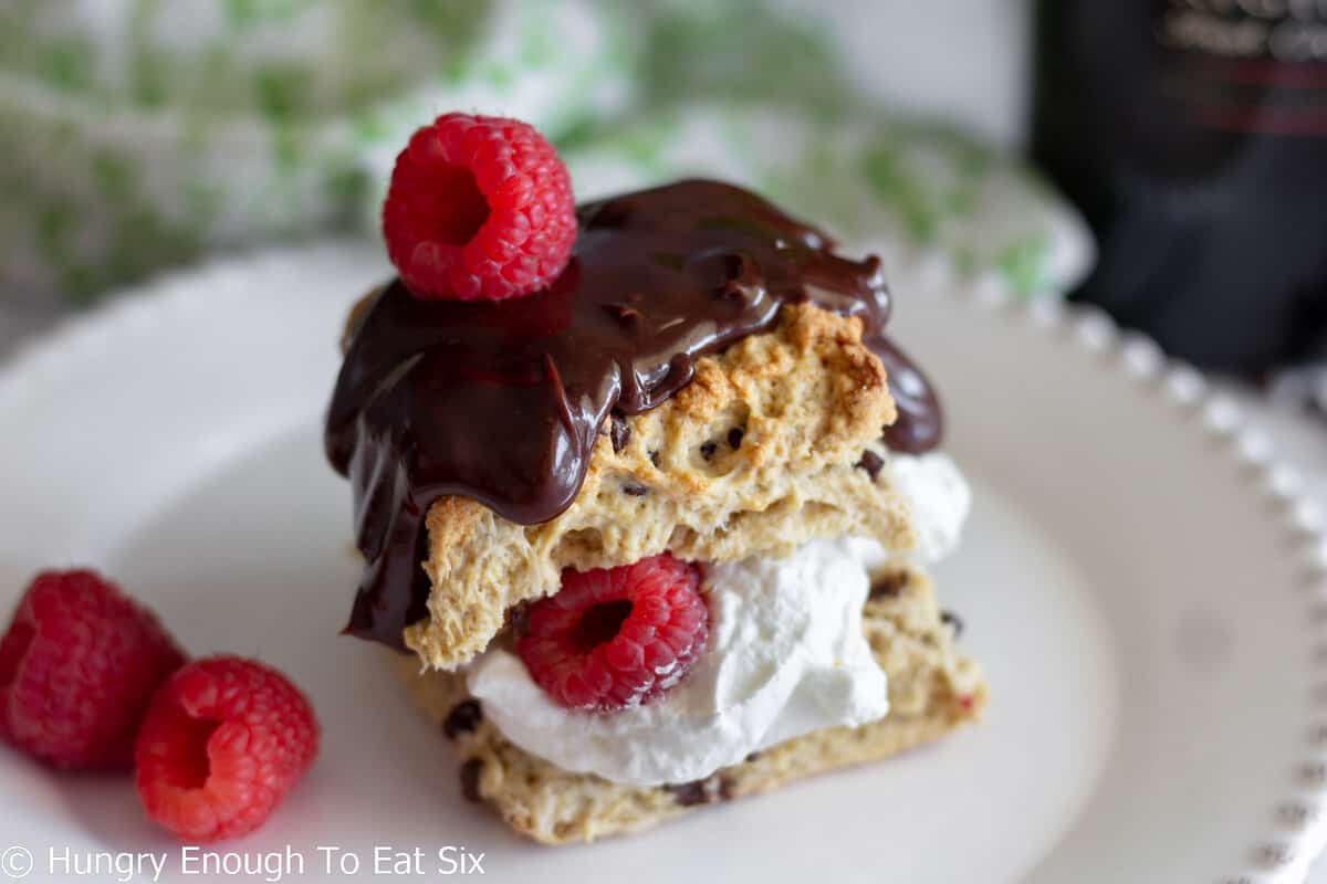 Plate with scone, whipped cream, chocolate, and berries.
