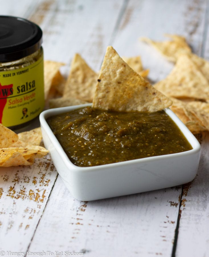 Salsa verde in a white dish with tortilla chips stuck in.