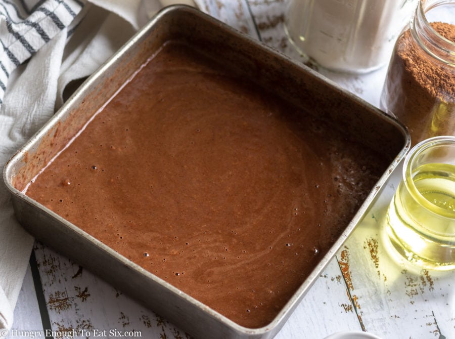 Chocolate cake batter in a square baking pan.