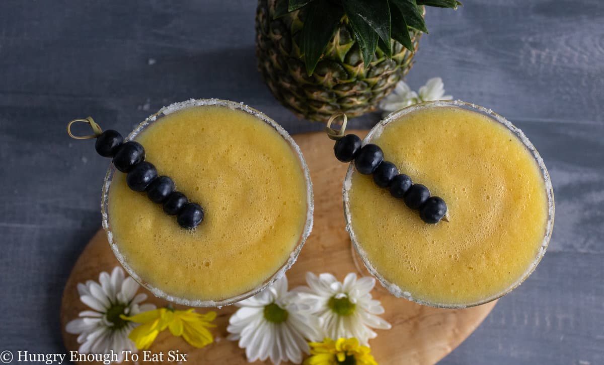 Glasses with blended pineapple and blueberry garnish