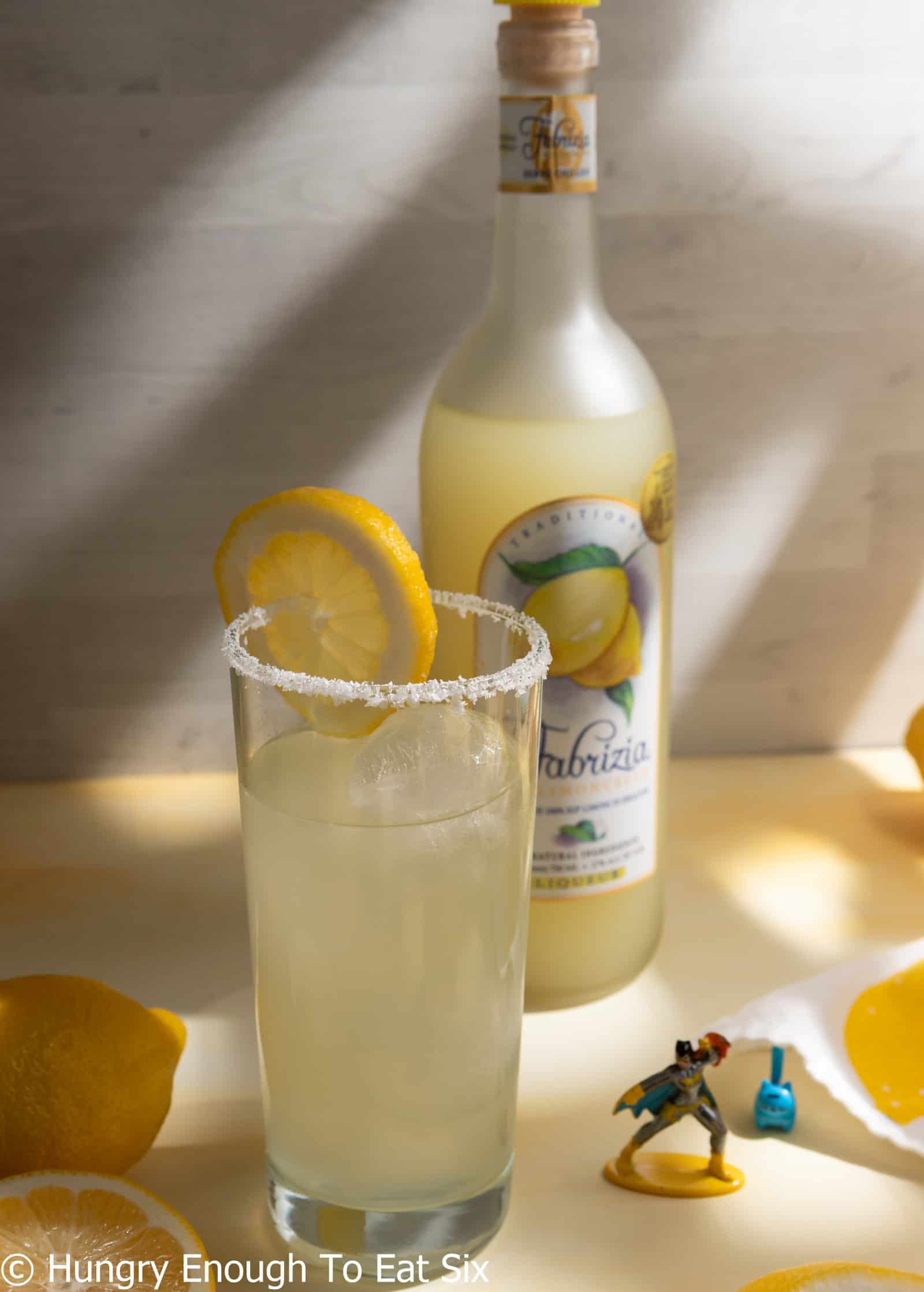 Tall glass with lemon margarita and lemon slice.