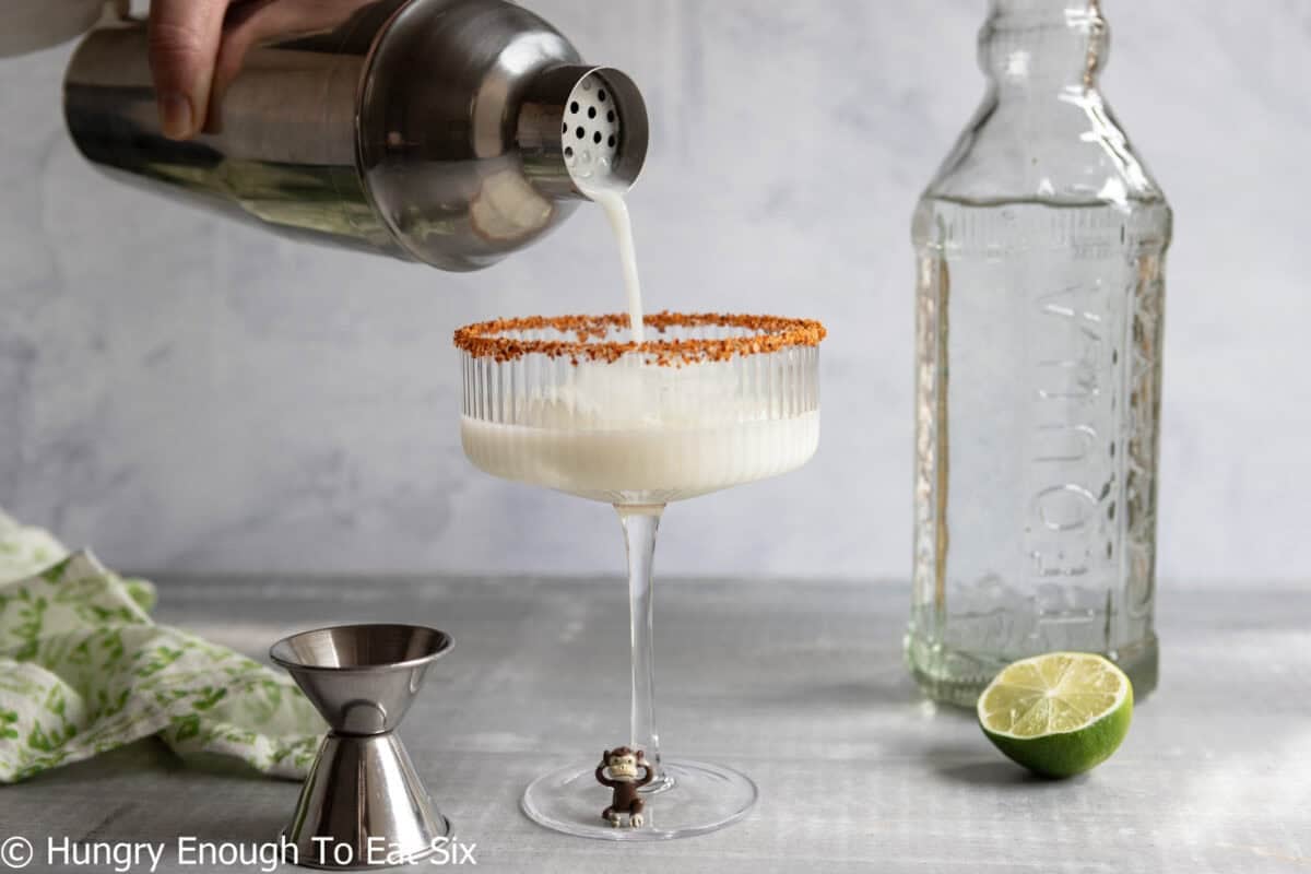 Coconut drink pouring from cocktail shaker into glass.
