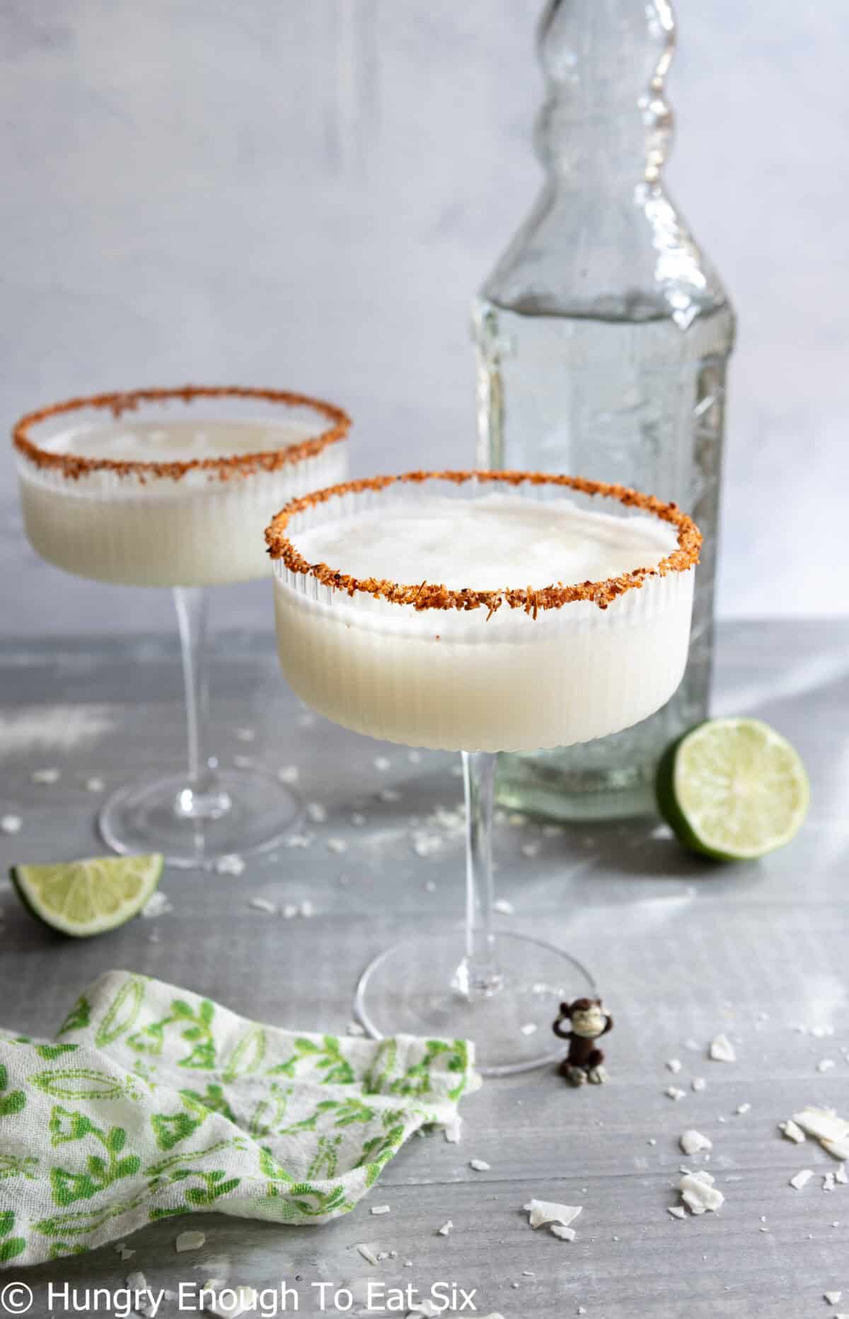 Two coconut tequila cocktails with sliced lime on table.