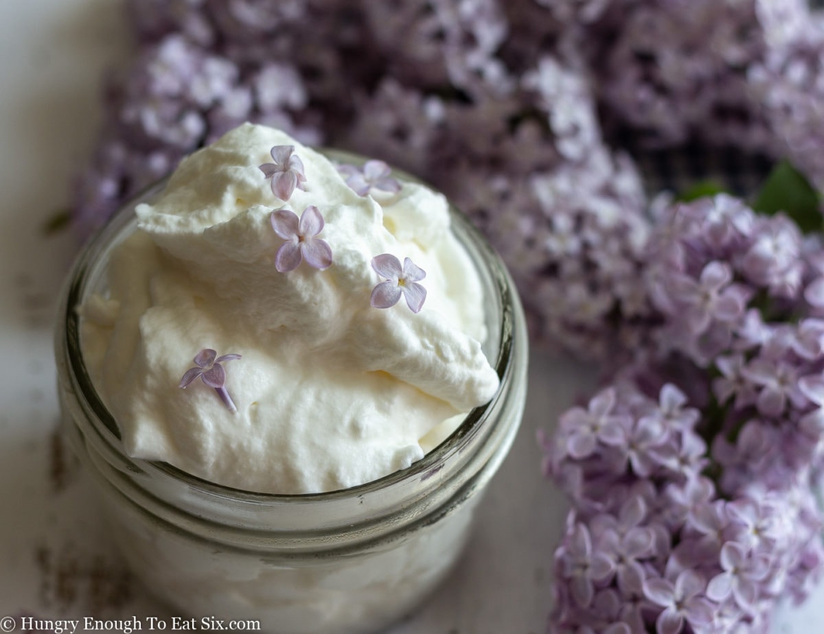 Infused whipped cream with purple lilacs behind. 