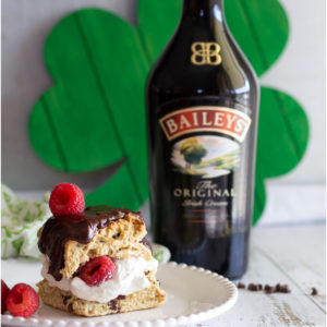 Scone with chocolate and cream next to a bottle of Baileys Irish Cream and a shamrock