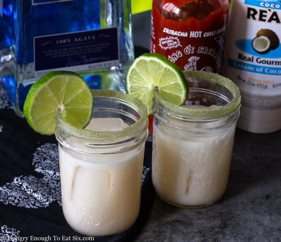 Coconut and lime margaritas with lime slices, tequila and hot sauce.