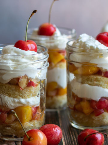 Three glass jars holding layered fruit and cream