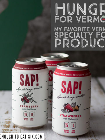 Three cans of Sap! sparkling water on a white wooden surface