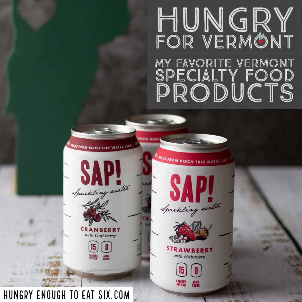 Three cans of Sap! sparkling water on a white wooden surface