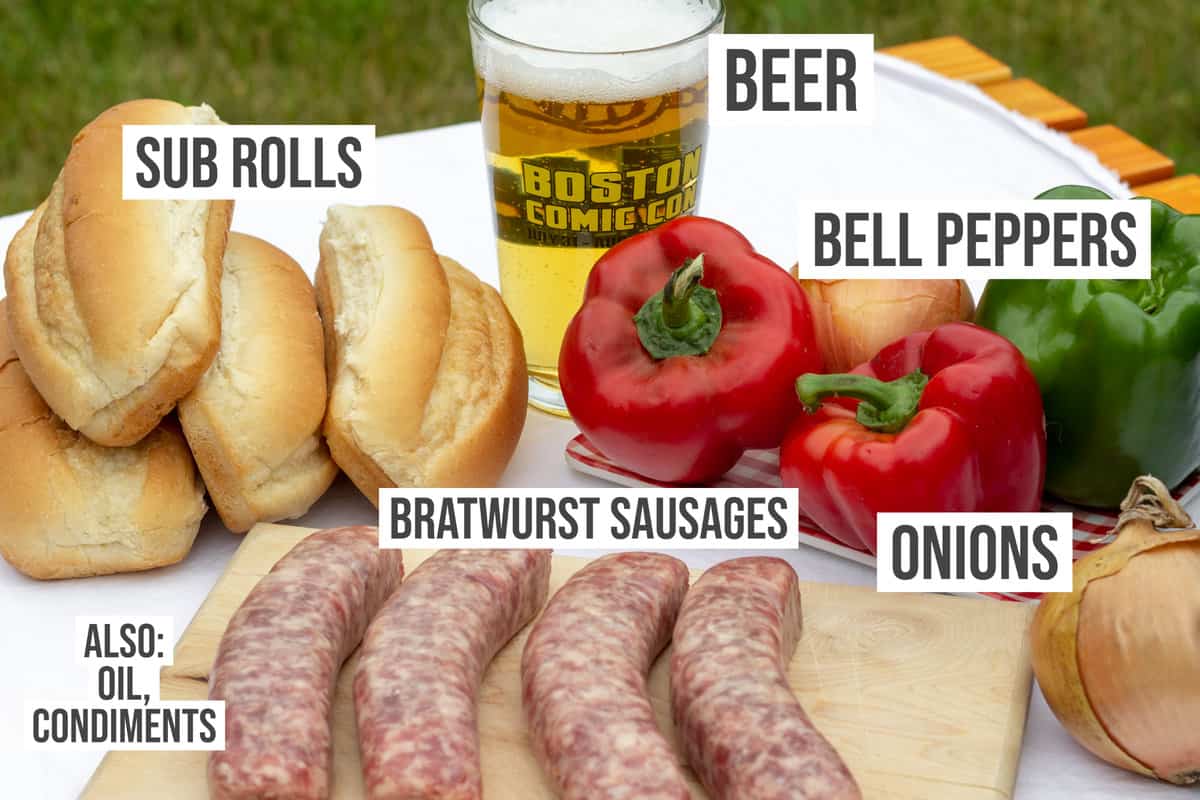 Raw sausages, bell peppers, sub rolls, and a glass of beer.