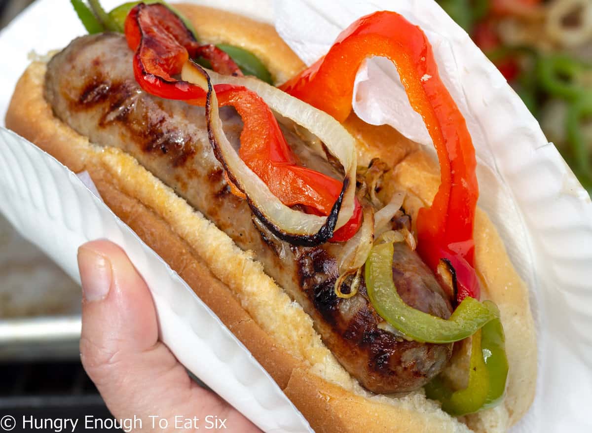 Grilled sausage in a roll with sliced peppers.