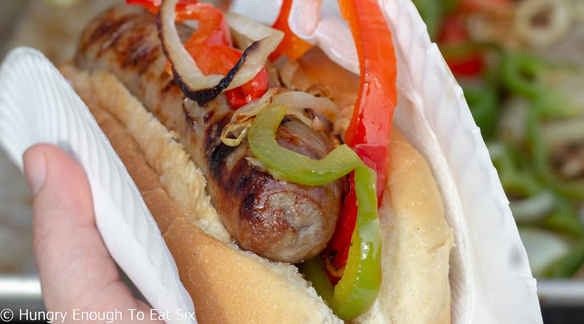Grilled sausage with sliced peppers in a roll.