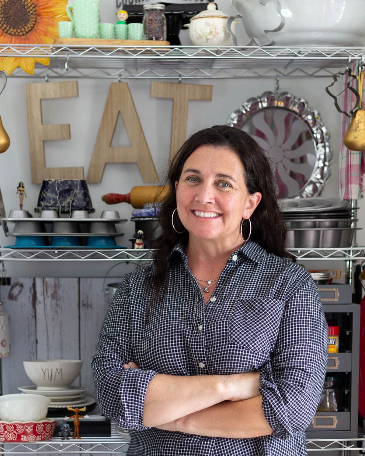 Woman smiling and arms folded in front of letters that spell "eat".