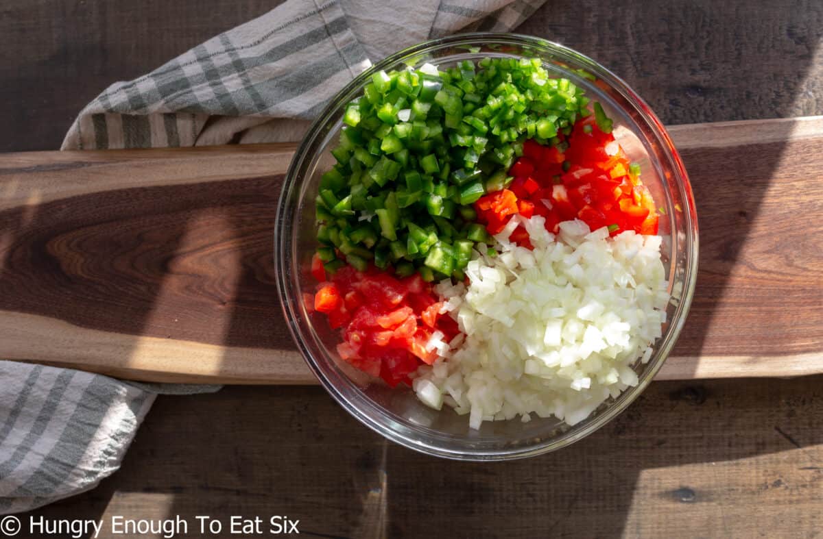 Glass bowl of chopped tomatoes, peppers, and onions.